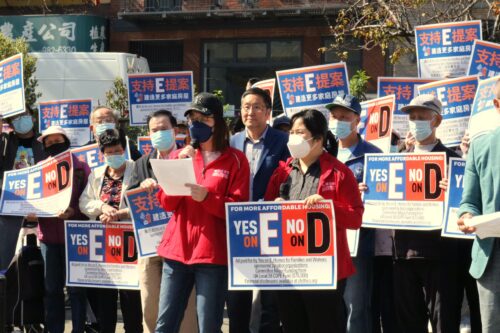 Yoyo, a CPA TWC Member Leader, speaks on Yes on E surrounded by other folks holding up Yes on E, No on D signs in English and Chinese.